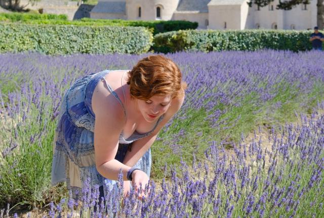 A student smells lilacs in a field of lilacs in Gordes, France.