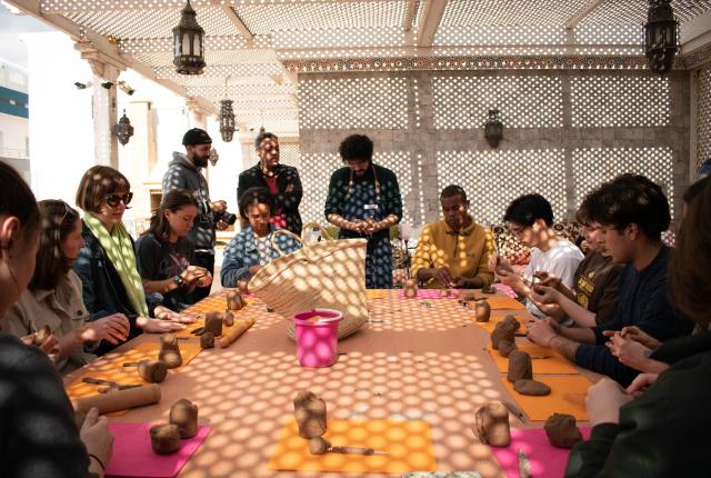 In Meknes, students sit around a table and mold blocks of clay.