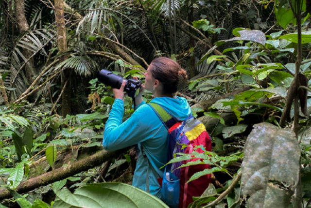Student holding a camera in the jungle