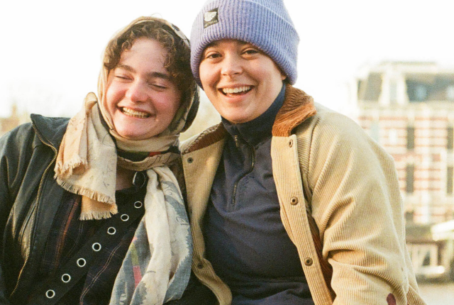 Two students sitting by the amstel in Amsterdam