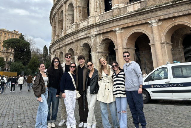 Students standing in front of the Colosseum smiling