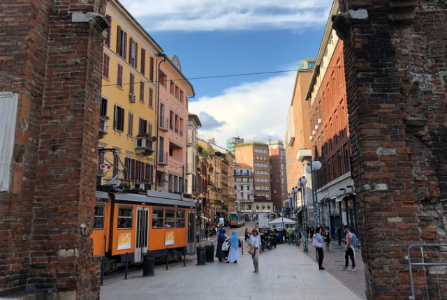 A bustling Milan street as viewed through a historic archway