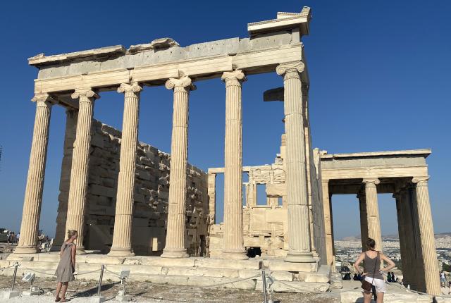 Ancient Greek temple ruins with tall columns under a clear blue sky. This alt text was added with Al; accuracy may vary.