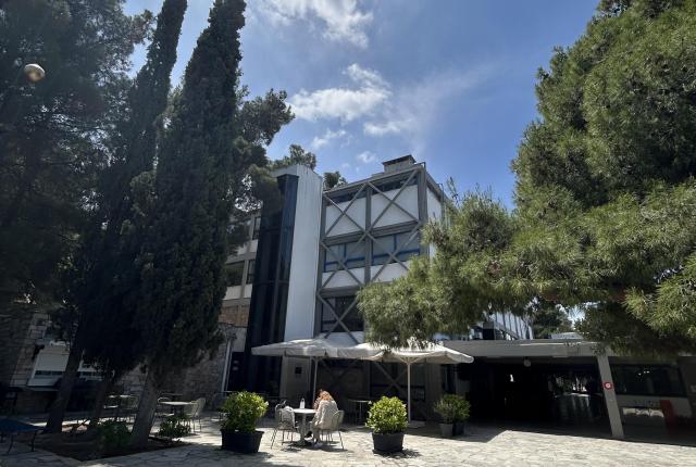 Modern building surrounded by trees under a clear blue sky. This alt text was added with Al; accuracy may vary.