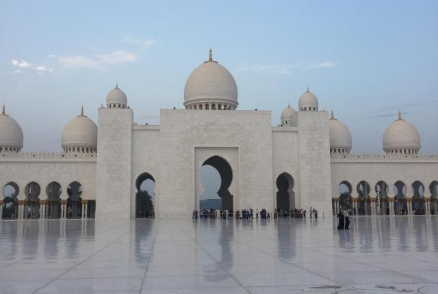 The Sheikh Zayed mosque in Abu Dhabi with domes, blue sky background.