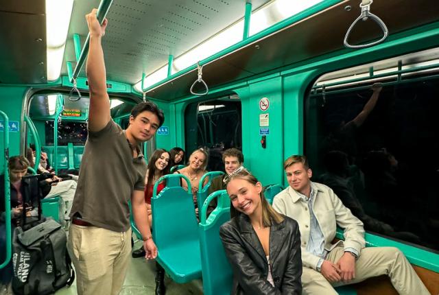 Several smiling students riding public transportation together