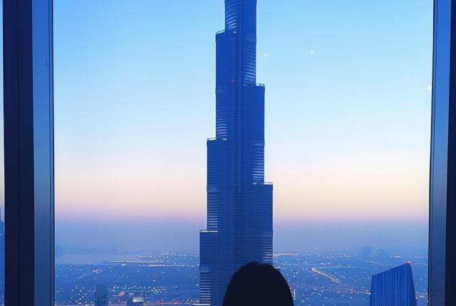person standing in front of a window with the burj khalifa in the background