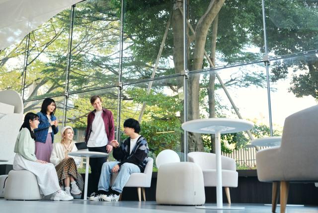 Students sitting and smiling indoors near a window at Musashi University
