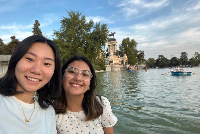 Two students smiling in front of the water at Retiro Park in Madrid, Spain