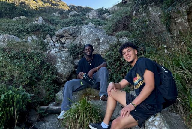 Two guys sitting on rocks in front of a blue sky in Cape Town.