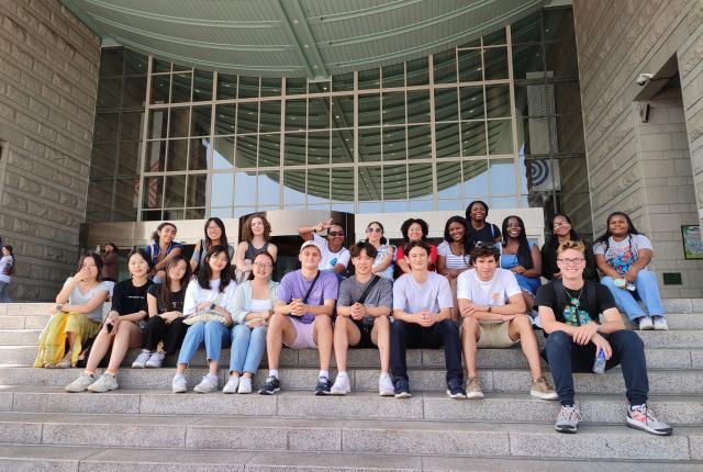 Students sitting on the steps and smiling while in Seoul, South Korea.