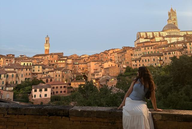 A student sitting on a ledge overlooking the city of Siena, Italy