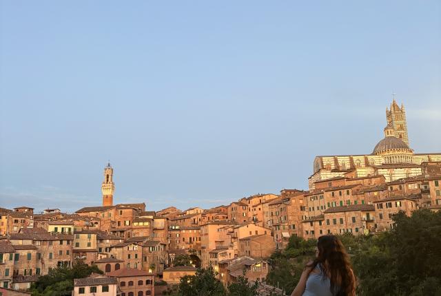 A student sitting on a ledge overlooking the city of Siena, Italy
