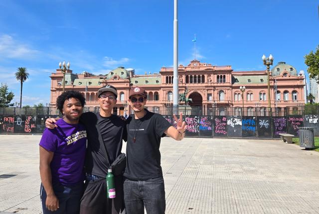 three students standing in front of La Casa Rosada