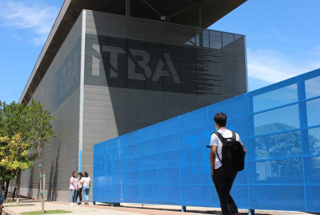 a student wearing a backpack walking toward an ITBA building