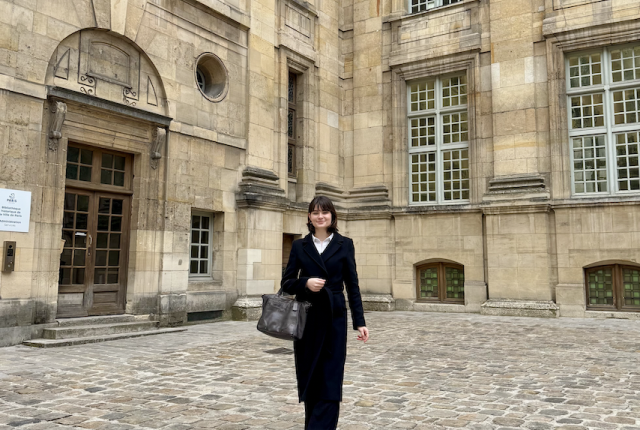 Student in business attire walking in front of parisian building