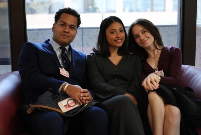 Three students sit in business professional attire on the EU Member States trip to Brussels, Belgium.