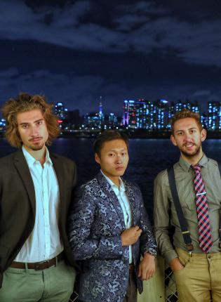 three students pose for a photo in front of the Seoul skyline at night