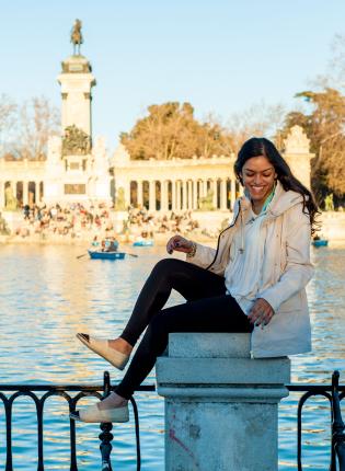 a student laughs while having her photo taken at Retiro Park Lake in Madrid