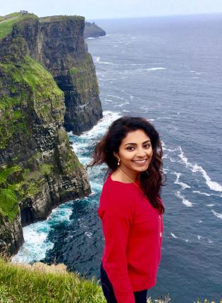 a student sits cliffside at the Cliffs of Moher