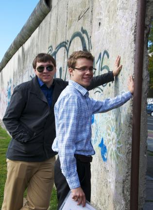 two student interns touching the Berlin Wall