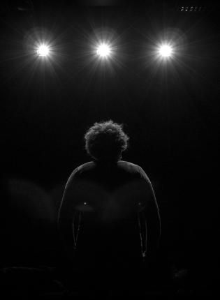 a student standing on stage facing the spotlights