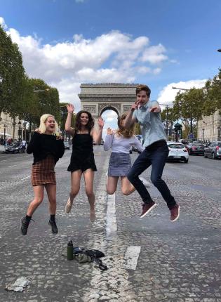 students jumping for a fun photo in front of arc de triomphe