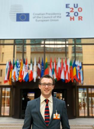 a student standing in front of European Union flags