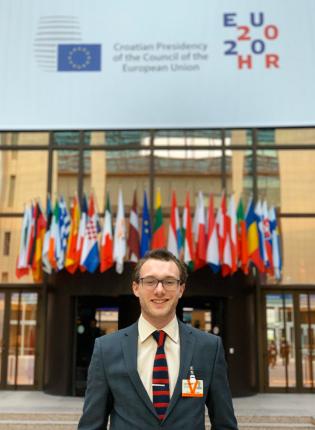 Male student standing in front of the EU council building