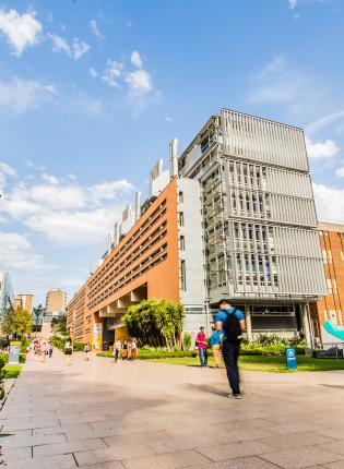 Students make their way to class on UNSW's campus, with tall brick buildings along the main walkway.
