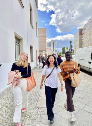Three students walk on the sidewalk in Berlin, Germany.