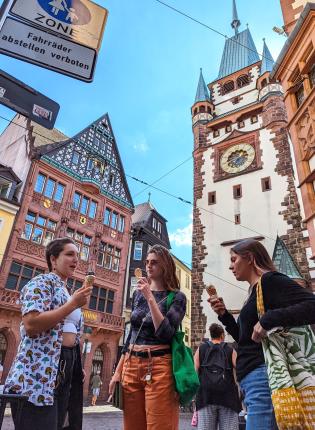 Three study abroad students eat ice cream in front of the Martinstor in Freiburg, Germany