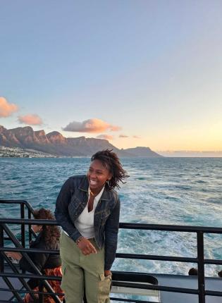 Student smiling in front of Cape Town ocean view