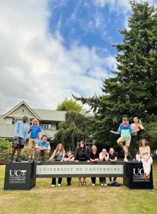 a group of students pose for a photo with the UC Canterbury sign