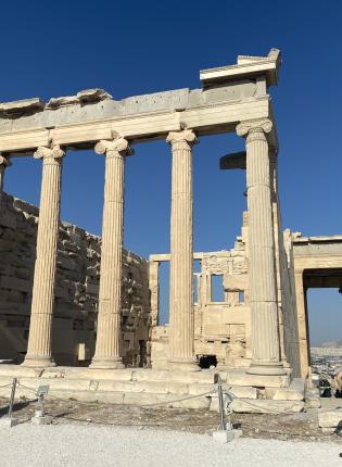 Ancient Greek temple ruins with tall columns under a clear blue sky. This alt text was added with Al; accuracy may vary.
