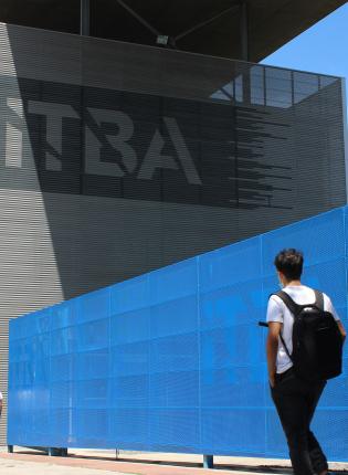 a student wearing a backpack walking toward an ITBA building