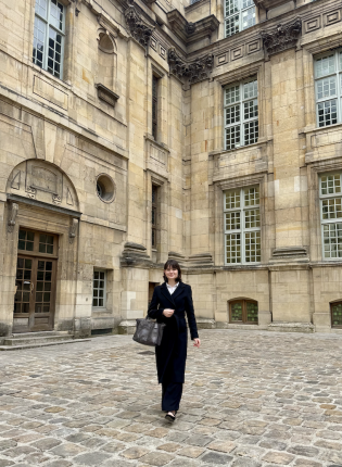Student in business attire walking in front of parisian building