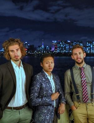 three students pose for a photo in front of the Seoul skyline at night