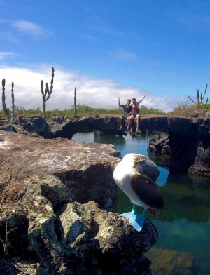 students pose for a photo in the background of where a blue footed booby is taking a nap