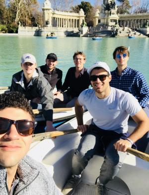 a group of guys pose for a photo in a boat at Retiro Park Lake in Madrid
