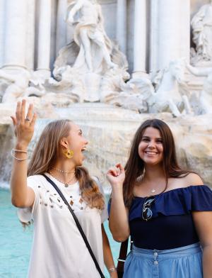 two students posing for a photo in front of Trevi Fountain in Rome as they toss coins in to make a wish