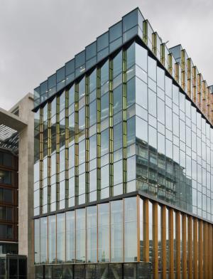 A large, modern building sits on the Conservatorium van Amsterdam's campus with reflective windows.