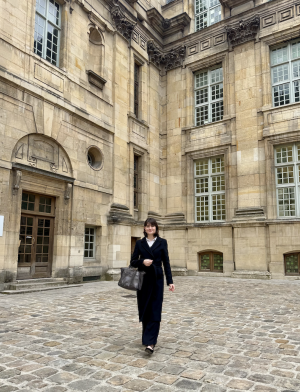Student in business attire walking in front of parisian building