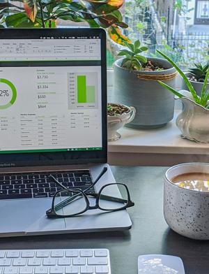 A laptop with the IES Abroad internship webpage on it, in front of a window with plants and near a cup of coffee