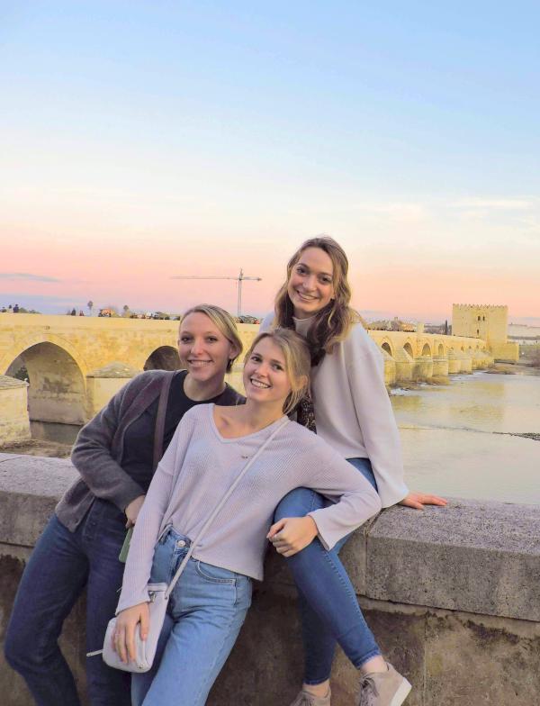 Three students stand on a bridge in Cordoba