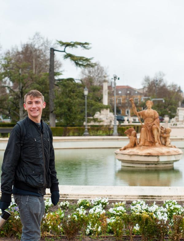 A student walking in front of one of the Fuentes de las Nereidas, a collection of fountains and sculptures dedicated to the beauty and kindness of the sea.