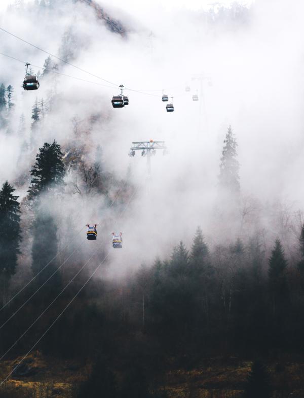 Ski lifts travelling to their destinations in the Austrian Alps on a foggy morning.