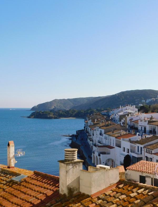 Houses and buildings on the coast of Cadaques, Spain. The buildings are all white with a red stucco roof.