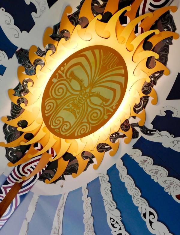 A ceiling mural depicting the sun in the sky, along with clouds and other unique detail work.