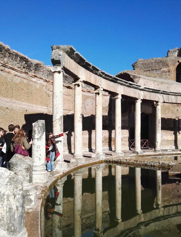On the left, there is a group of students and a professor. The professor is pointing to the columns and reflection pool at Hadrian's Villa.